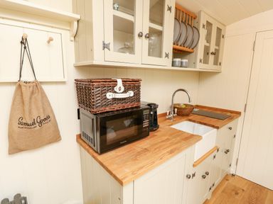 A kitchen with a microwave coffee maker sink and wooden countertop at The Happy Hut in Sopley near Christchurch
