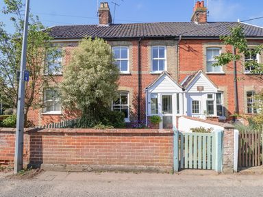 A row of brick terraced houses with small front gardens and gates in Reydon near Southwold