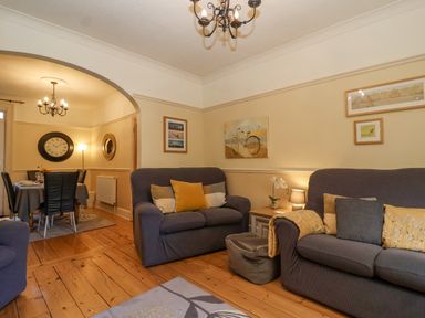A living room with two sofas and cushions and a dining area with a table and chairs at Green Gate Cottage in Reydon near Southwold