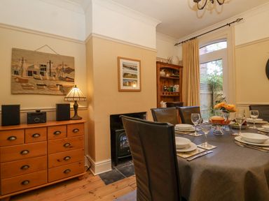 A dining room with a table set for six people and wooden furniture at Green Gate Cottage in Reydon near Southwold