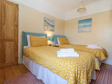A bedroom with two single beds with yellow polka dot bedspreads and towels on top at Green Gate Cottage Reydon near Southwold