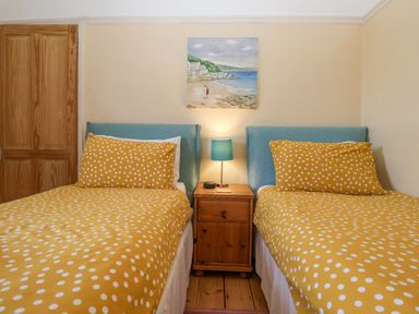 A bedroom with two single beds with yellow polka dot bedding and a bedside table with a lamp at Green Gate Cottage in Reydon near Southwold