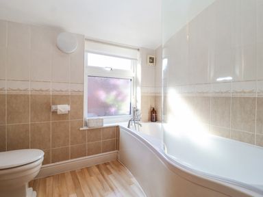 A bathroom with a toilet a bathtub and a window at Green Gate Cottage in Reydon near Southwold