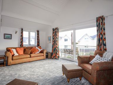 A living room with sofas cushions ottoman and large sliding glass doors at Seaside Sanctuary in Trearddur Bay
