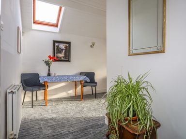 A seating area with two gray chairs and a table with a blue tablecloth under a skylight at Seaside Sanctuary in Trearddur Bay