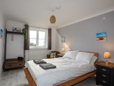 A bedroom with a bed lamps bedside tables and a window at Seaside Sanctuary in Trearddur Bay