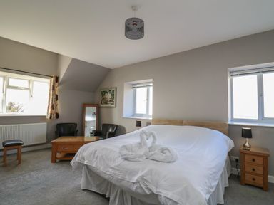 A bedroom with a double bed with folded towels on it two chairs and a wooden coffee table at Mynydd ar Mor in Barmouth