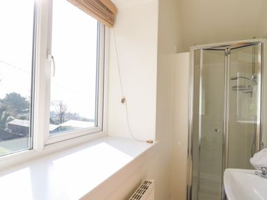 A bathroom with a window radiator shower cubicle and a sink at Mynydd ar Mor in Barmouth