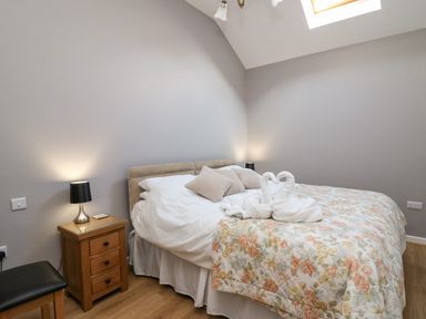 A bedroom with a double bed with swan towel decoration bedside tables with lamps and a skylight at Mynydd ar Mor in Barmouth