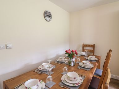 A dining table set with plates bowls glasses cutlery and a flower vase at Awel y Bryn in Rhayader