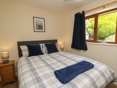 A bedroom with a double bed nightstands with lamps a window and dark curtains at Awel y Bryn in Rhayader