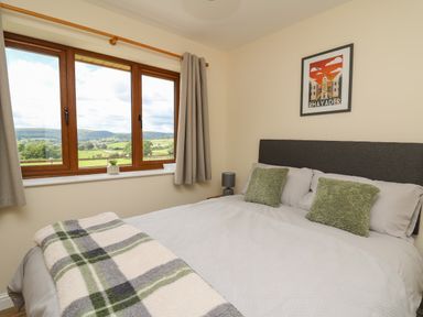 A bedroom with a bed near a window showing a countryside view at Awel y Bryn in Rhayader