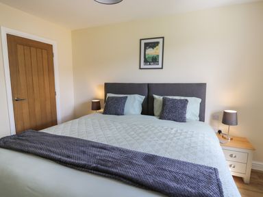 A bedroom with a double bed two bedside tables with lamps and a framed picture above the bed at Awel y Bryn in Rhayader