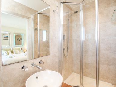 A bathroom with a round white sink and a glass shower enclosure at Sunset View in Castletown Portland