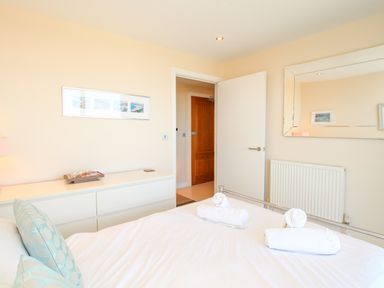 A bedroom with a bed with rolled towels on it a dresser with shells a mirror and two doors at Sunset View in Castletown Portland