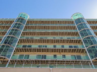 A multi-story building with glass balconies and two glass elevators on each side at Sunset View in Castletown Portland
