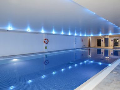 An indoor swimming pool with blue lighting and a life ring on the wall at Sunset View in Castletown Portland