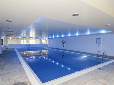 An indoor swimming pool with blue lighting and tiled floor at Sunset View in Castletown Portland