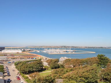 A coastal area with a marina filled with boats a parking lot trees and buildings at Sunset View in Castletown Portland