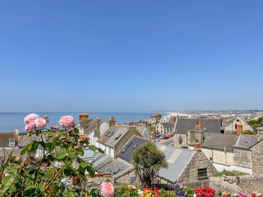 A coastal town with stone houses pink flowers and a view of the sea at Sunset View in Castletown Portland