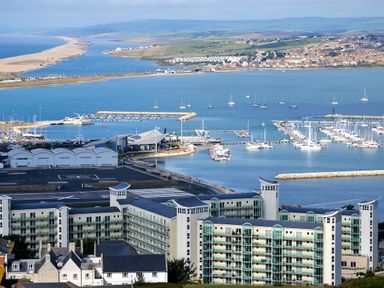 A marina with boats docked and a large building in the foreground at Sunset View in Castletown Portland