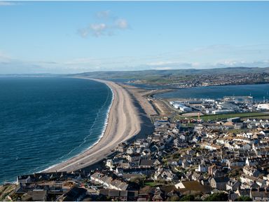 A coastal town with a long sandy beach and buildings near the shore at Sunset View in Castletown Portland