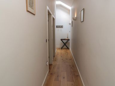 A hallway with wooden floor a small table and wall decorations at The Coach House Bamburgh