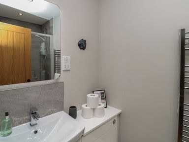 A bathroom sink with soap dispenser and stacked toilet paper rolls on cabinet at The Coach House in Bamburgh