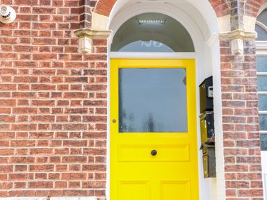 A yellow front door with frosted glass in a brick wall with mailboxes on the right at Flat 3 in Cromer