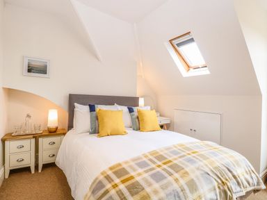 A bedroom with a double bed yellow pillows bedside tables and a skylight window at Flat 3 in Cromer