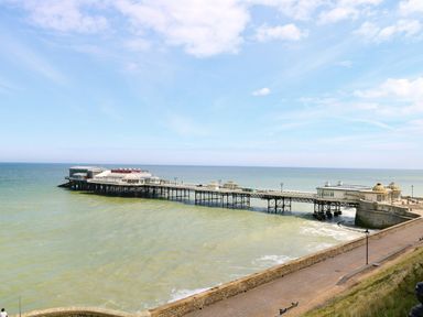 A pier extending into the sea with buildings on it and a walkway along the shore at Flat 3 in Cromer