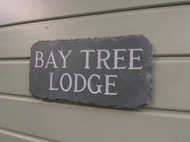 A sign on a wall with the text Bay Tree Lodge at Bay Tree Lodge in Cartmel