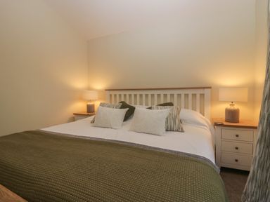 A bedroom with a double bed pillows bedside tables and lamps at Bay Tree Lodge in Cartmel