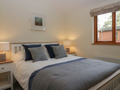 A bedroom with a bed with pillows and lamps on bedside tables at Bay Tree Lodge in Cartmel