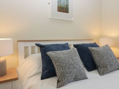 A bedroom with a bed with four pillows and two bedside tables with lamps at Bay Tree Lodge in Cartmel