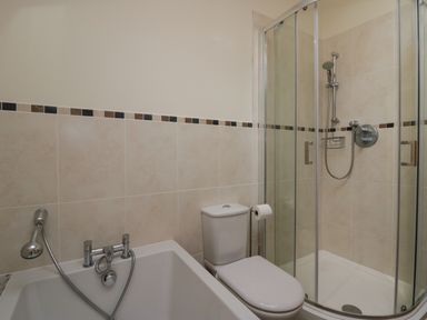 A bathroom with a bathtub toilet and glass shower enclosure at Bay Tree Lodge in Cartmel