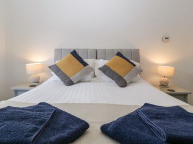 A bedroom with a bed featuring two square pillows and bedside tables with lamps at Ty Glas in Ogmore-by-Sea near St Brides Major