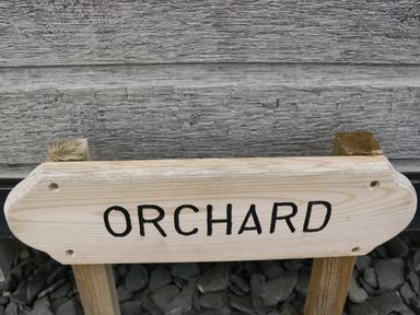 A wooden sign with the word orchard in black letters outdoors at Orchard in Dalton-In-Furness