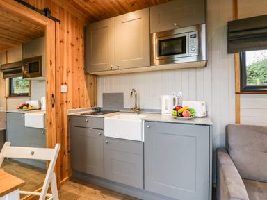 A compact kitchen with grey cabinets a microwave sink kettle toaster and a plate of fruit at Orchard Dalton-In-Furness