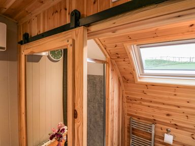 A wooden bathroom with a sliding mirror door skylight and towel rack at Orchard in Dalton-In-Furness