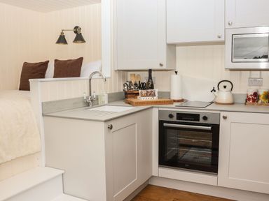 A kitchen corner with a sink oven microwave and kettle next to a bed at Hillside Hut Radbourne near Ashbourne
