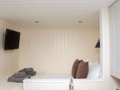 A small bedroom with a bed pillows folded towels and a wall-mounted television at Hillside Hut Radbourne near Ashbourne