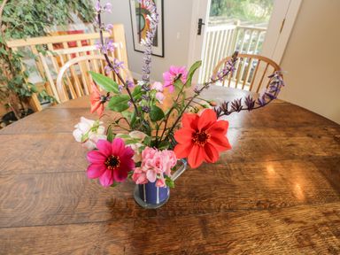 A wooden dining table with a colorful flower arrangement in a blue and white vase at The Barn at Westhall Cottage Fulbrook near Burford