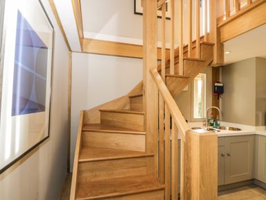 A wooden staircase next to a kitchen sink with cabinets at The Barn at Westhall Cottage Fulbrook near Burford
