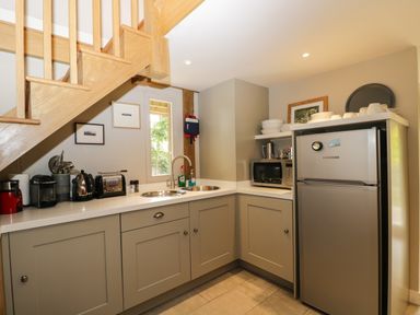 A kitchen under a wooden staircase with countertop appliances and a refrigerator at The Barn at Westhall Cottage in Fulbrook near Burford