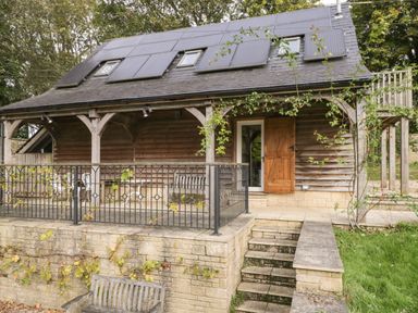 A wooden house with solar panels on the roof and a stone patio with stairs at The Barn at Westhall Cottage Fulbrook near Burford