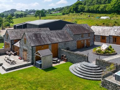 An outdoor area with stone buildings and a hot tub at Hay Store in Corwen