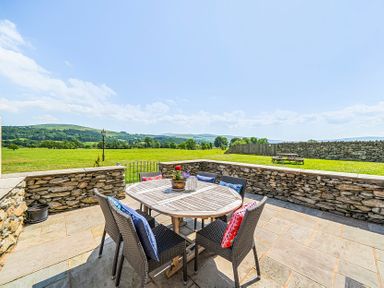 An outdoor dining area with a table and chairs at Hay Store in Corwen