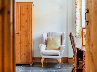 A living room with an armchair and wardrobe at Hay Store in Corwen