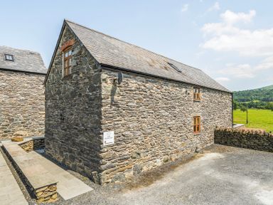 A stone building with windows and a sign at Hay Store in Corwen